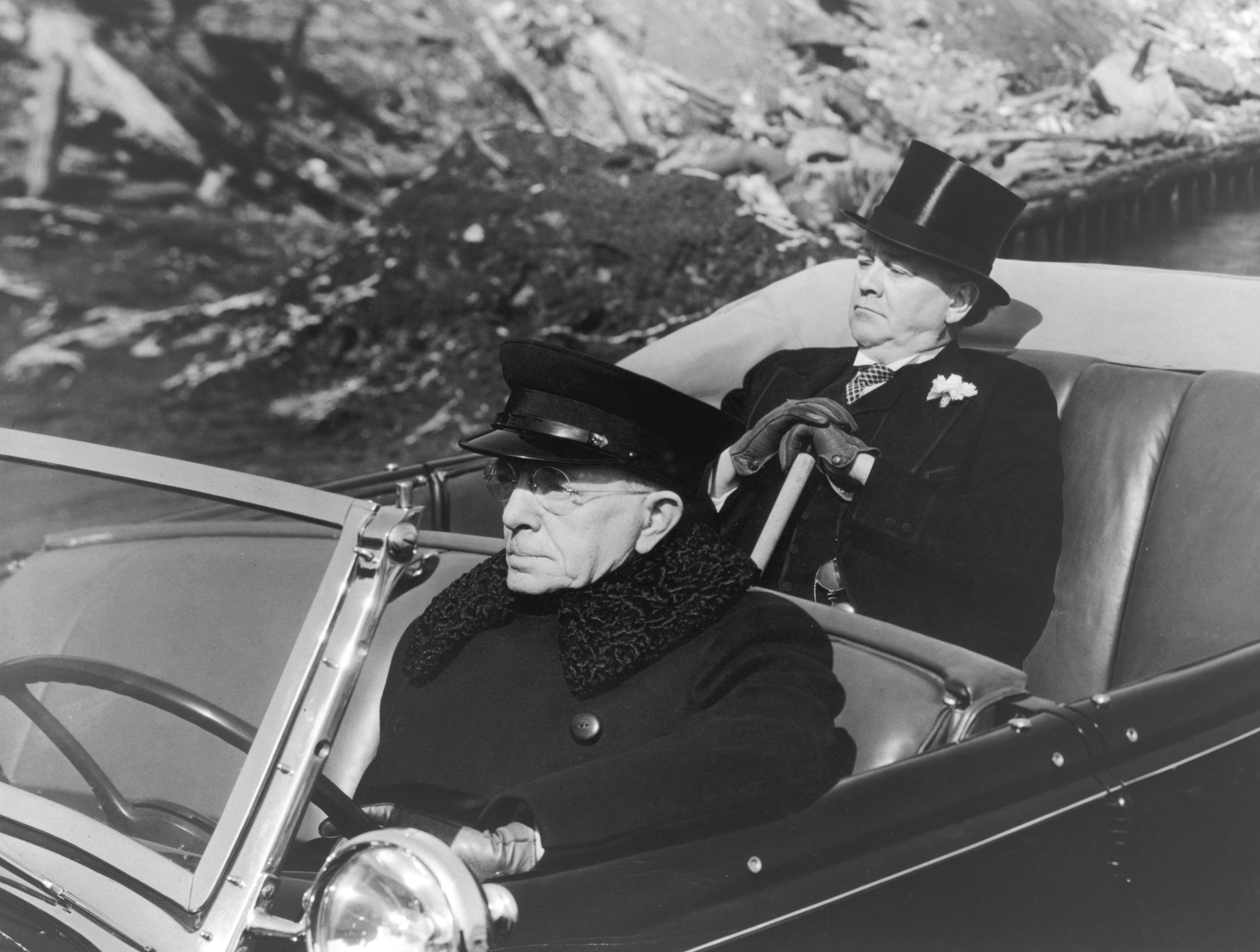 A dapper gentleman and his chauffeur in a convertible limousine, circa 1925