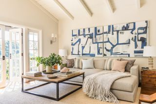 white living room with doors to the garden, shiplap vaulted ceiling, artwork, sofa, coffee table, rug, wooden floor