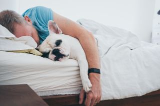 A man and a dog asleep in a bed