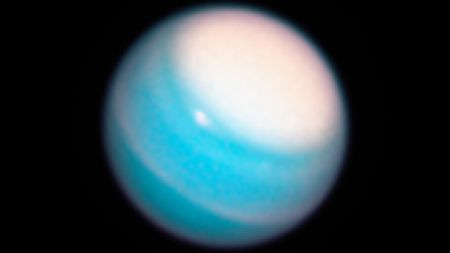 A blurry image of a blue planet with a large white storm cloud enveloping the upper half