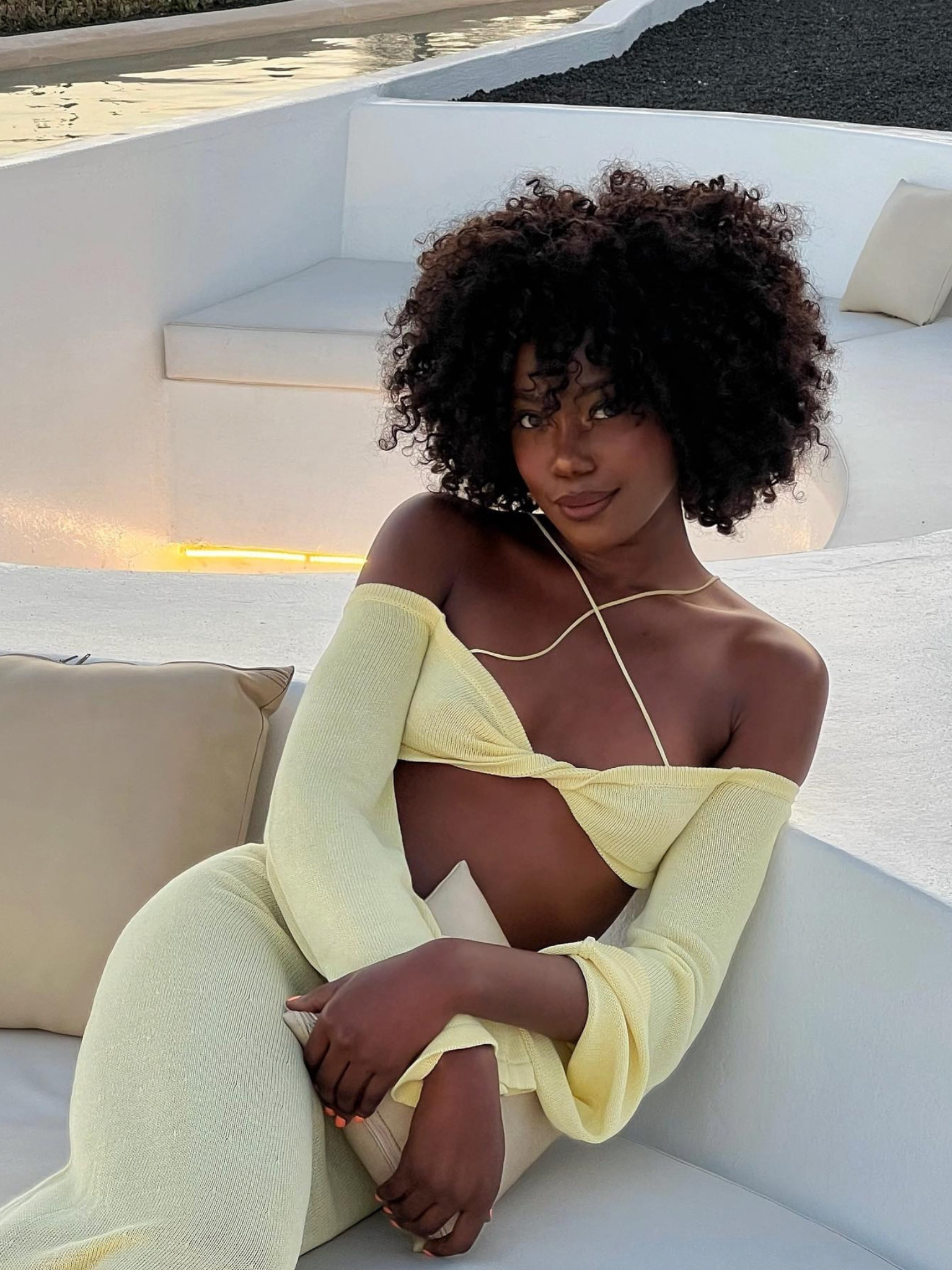 A woman with a fringed afro haircut, wearing a yellow dress.