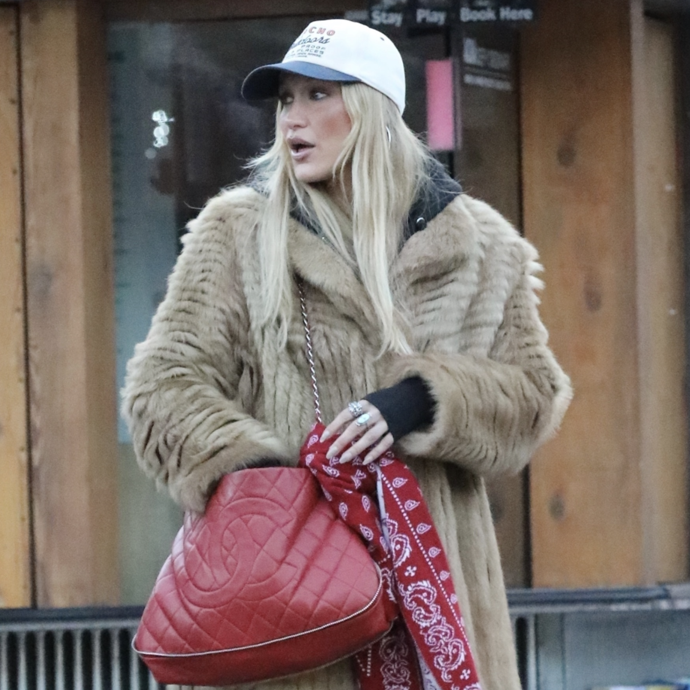 December 29, 2025 Bella Hadid wears a stylish fur coat and carries a chic red Chanel bag, as she is spotted hanging out with Brooks Nader in Aspen.
