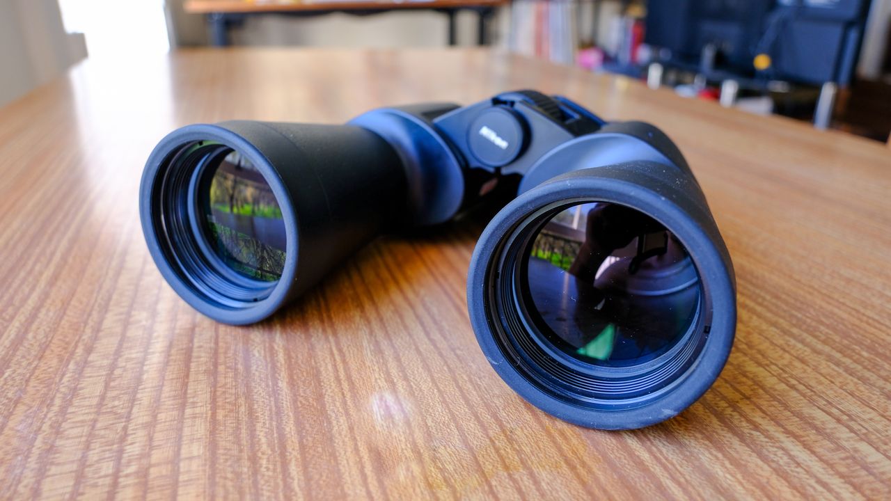 The Nikon Action Zoom 10-22x50 binoculars on a wooden table.