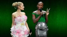 Ariana Grande, dressed in pink and white, and Cynthia Erivo, dressed in green and silver, at a press event for "Wicked"