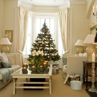 living room with cream wall christmas tree and candle on table