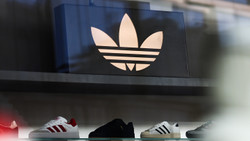 Adidas shoes on a black wall with Adidas logo in white about them