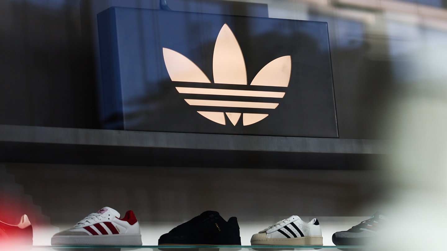 Adidas shoes on a black wall with Adidas logo in white about them