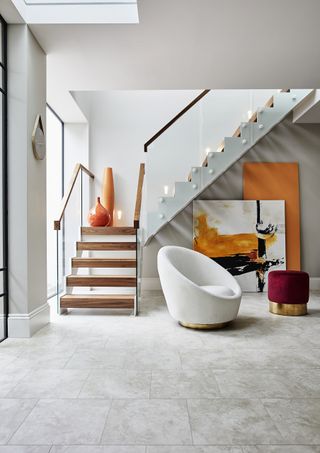 modern staircase in hallway with stone flooring, orange accents