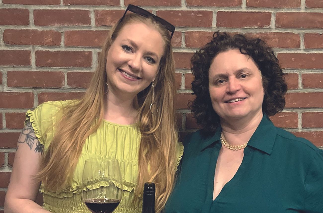 two women, one with a glass of wine