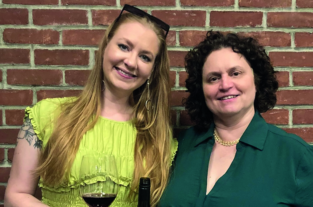 two women, one with a glass of wine