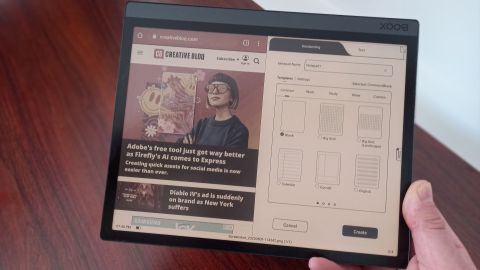 Hand holding Onyx Boox Tab Ultra C showing split screen between Creative Bloq website and notetaking app