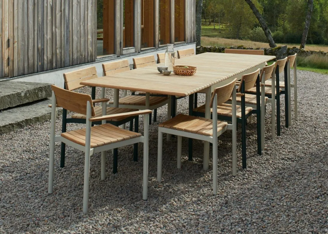 large wood and metal table and chairs in the middle of a gravel courtyard