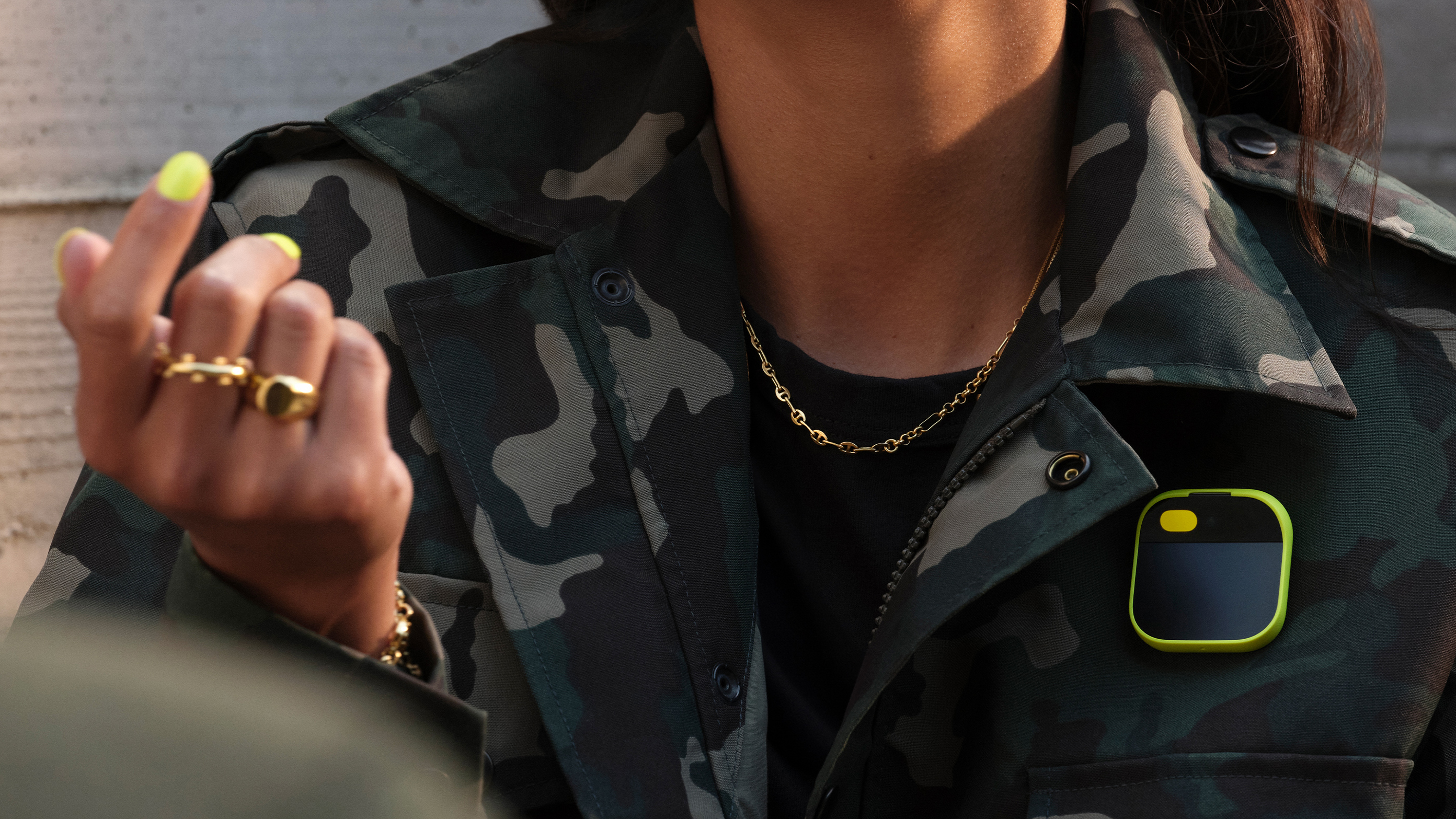 A person wearing the Humane AI Pin on a camouflaged jacket