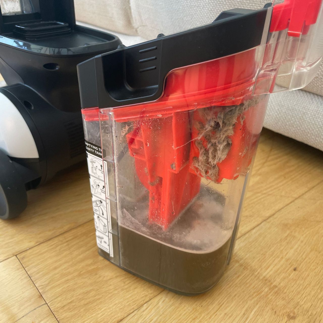 dirty water chamber of the Shark CarpetForce Upright Carpet Cleaner, full of brown water