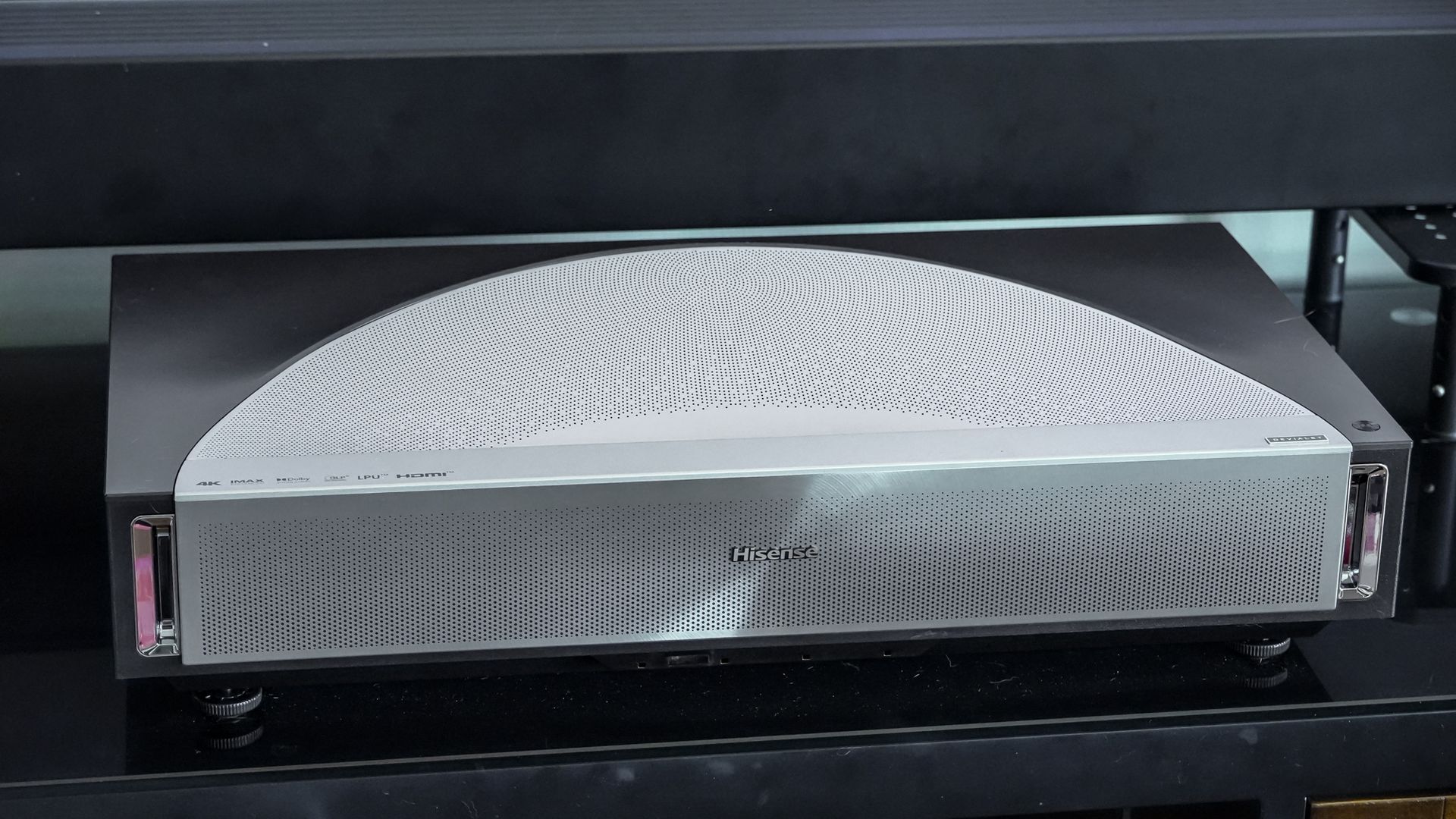 A Hisense PX4 Pro projector on a home media center shelf