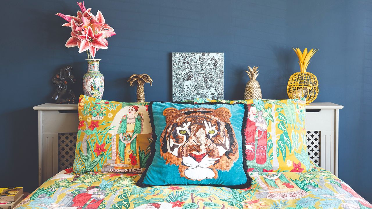 A bed with a colourful bed linen and a tiger cushion