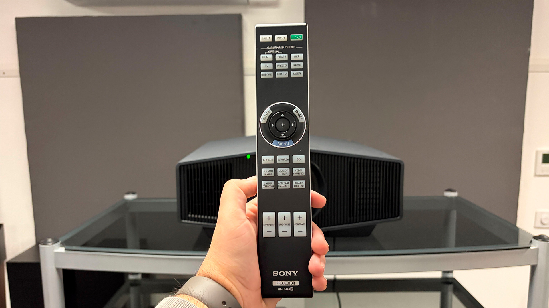 Sony Bravia Projector 7 home cinema projector remote control held in hand in front of projector