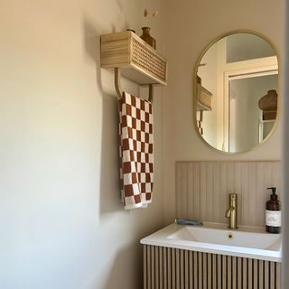 bathroom vanity with brass mirror and wall shelf with towel rail