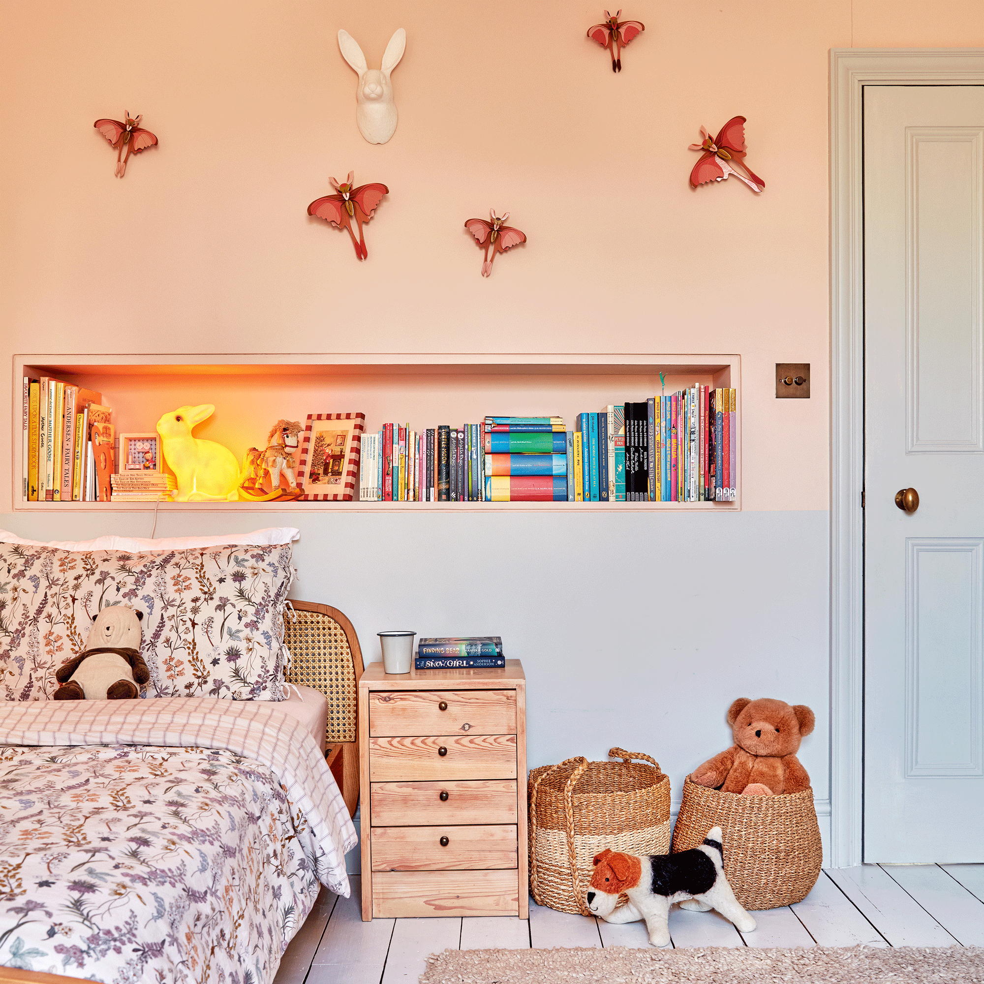a child's bedroom with two-tone pale pink and blue painted walls and a bed with patterned bedding