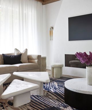 A living room with white limewash walls, triangular coffee tables, and a fireplace