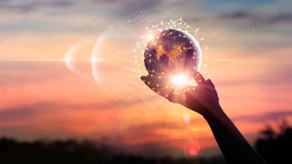 person holding tiny globe surrounded by lights in hand