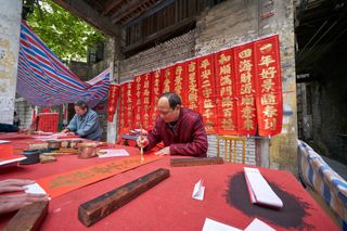 A calligrapher in Foshan, China, makes couplets — banners with wishes of good fortune and long life — for the Spring Festival.
