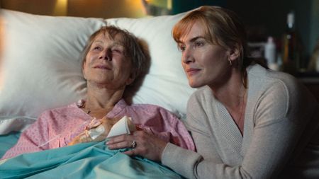 Helen Mirren lays in a hospital bed while Kate Winslet holds her hand