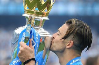 Manchester City midfielder Jack Grealish holding and kissing the Premier League trophy