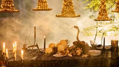 Smoky Anthropologie Halloween 2026 tablescape featuring dramatic candelabras, glowing witch hats, and skull-and-snake motif accents scattered throughout 