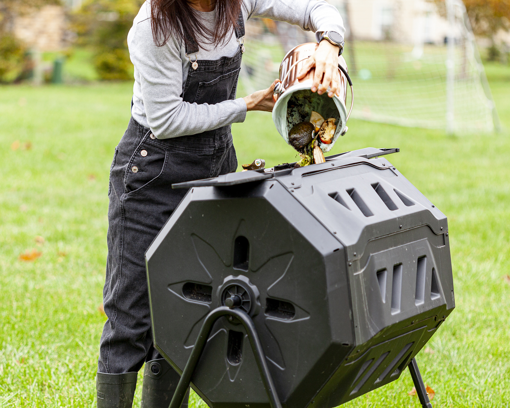 Gardener adds organic waste to tumbling composter