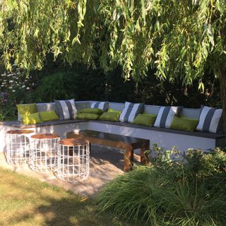 an L-shaped built-in garden seating area in a garden with trees overhead