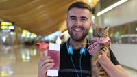 Happy man holding his cat at the airport