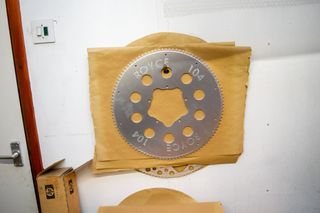 A 104 tooth silver Royce chainring hanging on a wall