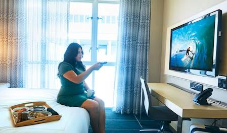 Female traveler watching TV in a hotel room. 