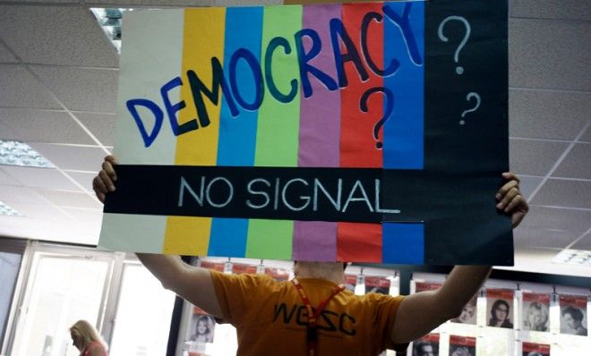 An employee of Greek public broadcaster ERT holds a sign inside the corporation&amp;#039;s headquarters, June 13.