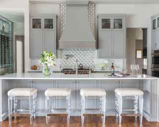 Light gray kitchen island with contemporary bar stools and fresh flowers on counter