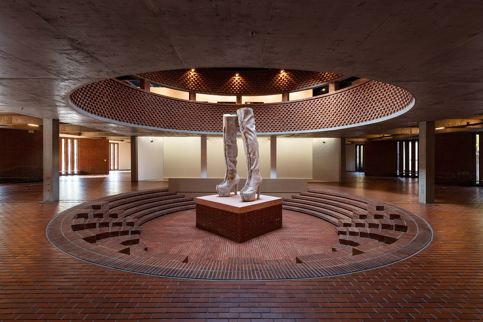 Large sculpture in middle of gallery of white pair of knee length boots
