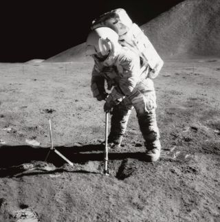 Apollo 15 astronaut James Irwin uses a scoop to dig in the lunar soil in front of Mount Hadley.