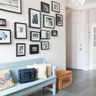 hallway with picture frames and white wall and blue bench