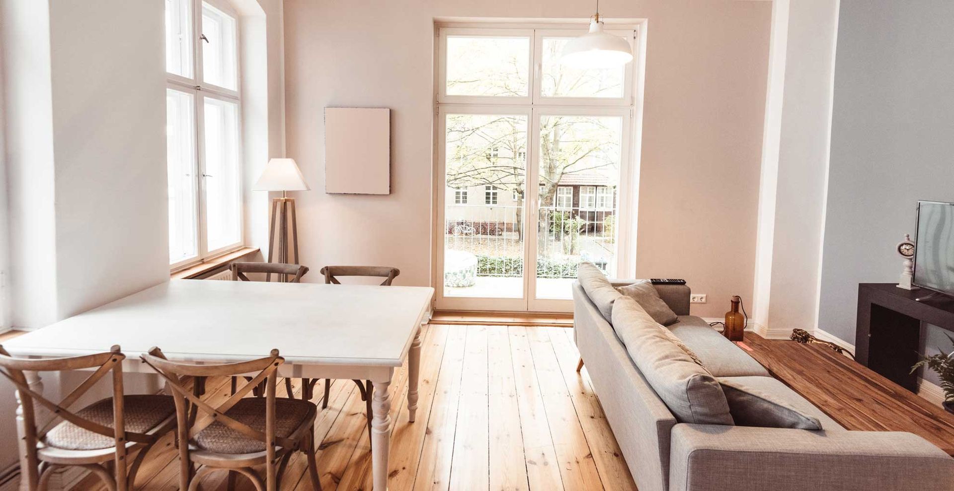 An arpartment living room with a small dining table behind a couch to show how to transform a living room on a budget by zoning the space by rearranging the furniture