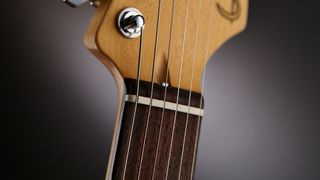 Detail of the Tusq nut on a Suhr Classic Pro electric guitar with an Olympic White finish