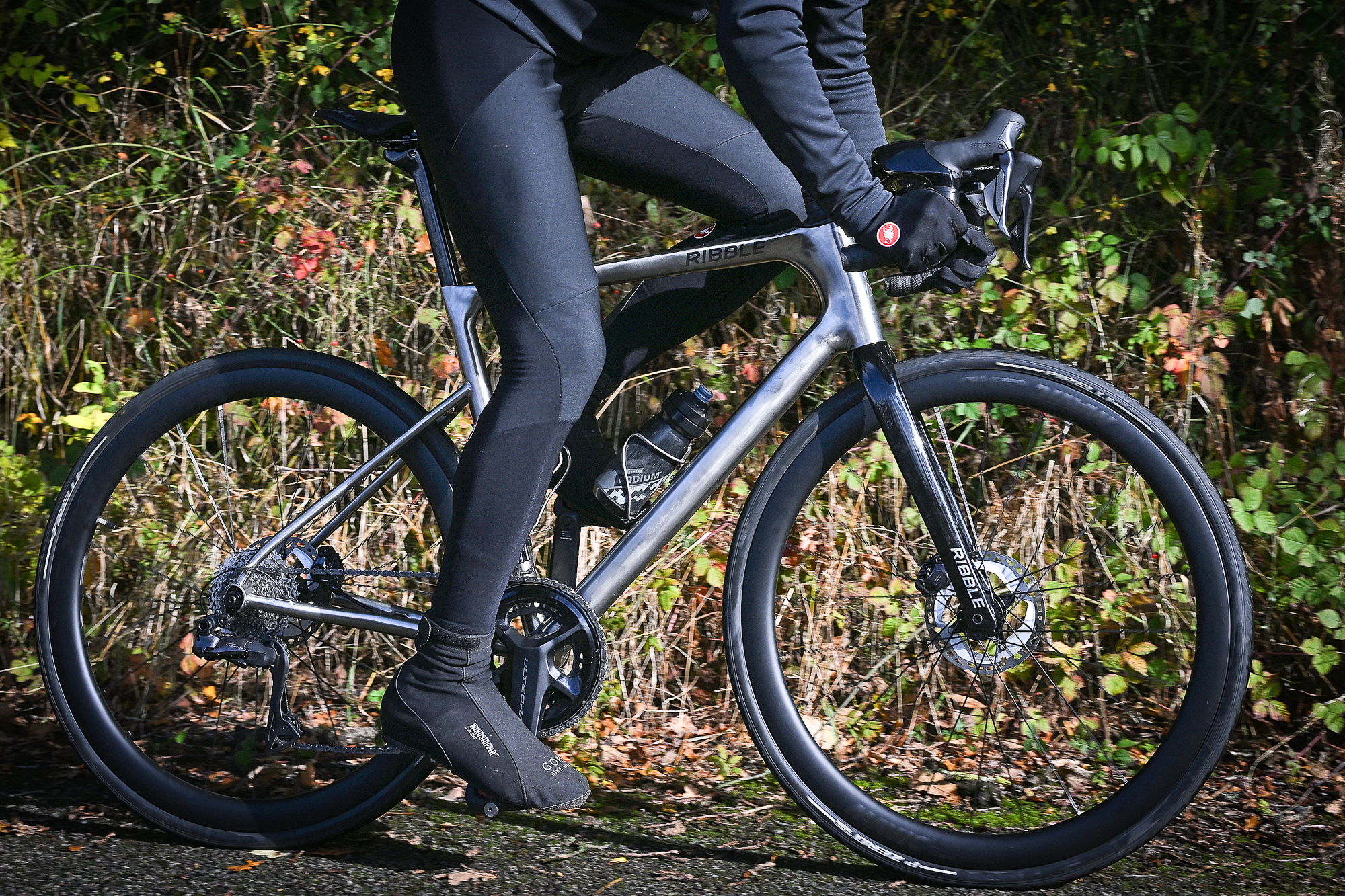 man riding a titanium bike on a lane showing mainly the bike