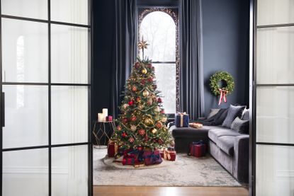 An artificial lit up Christmas tree in a dark blue living room
