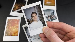Instax Mini prints layed out next to each other with one held in a hand