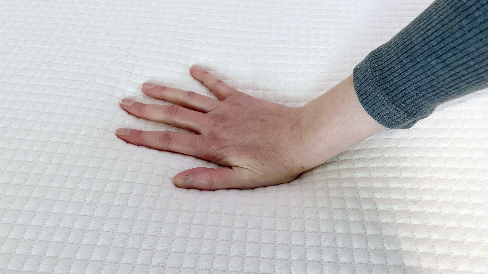 A hand pushing down onto a Simbatex Foam Mattress