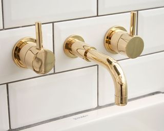 Brass taps above white basin
