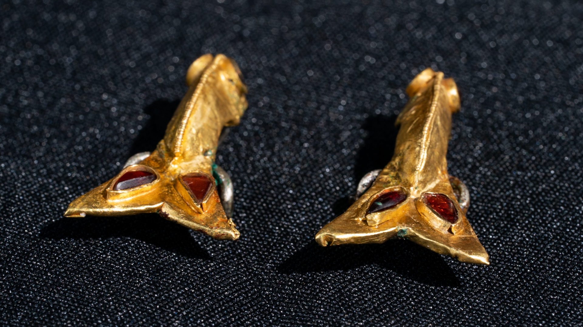 A close-up of gold brooches with red jewels