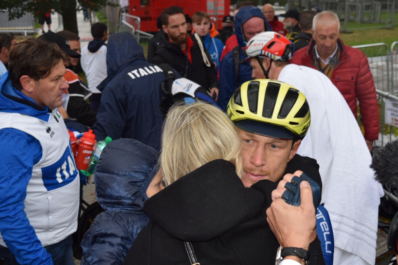 Matteo Trentin stares into the distance while hugging a family member