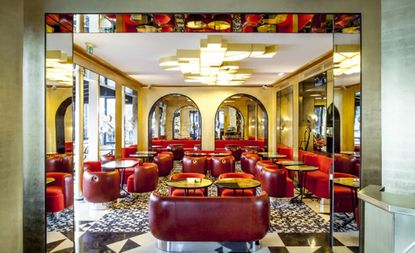 Red leather single and double couches, round single tables, checked and patterned black and white floor tiling