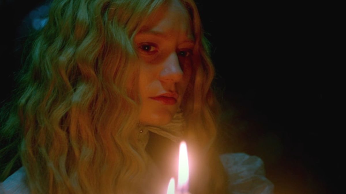 Mia Wasikowska looks worried as she walks by candlelight in Crimson Peak.